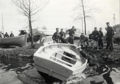 811897 Afbeelding van het te water laten van een boot van de Wilhelminagroep zeeverkenners op De Punt, het terrein van ...